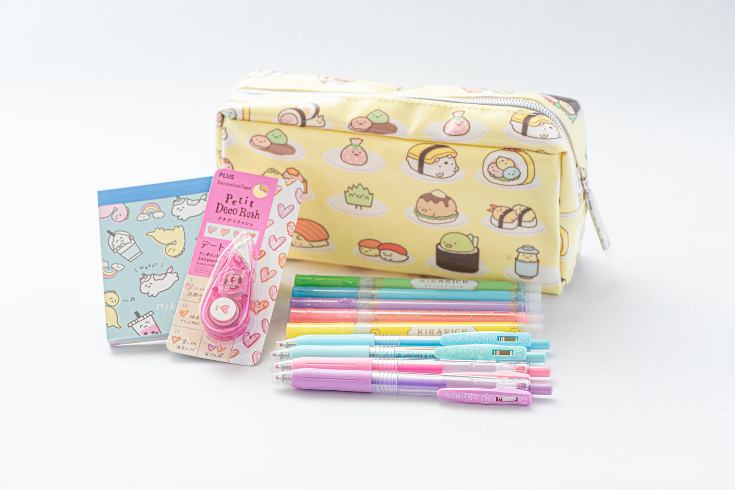 Yellow sushi-print pencil pouch with Sumikko Gurashi characters, markers, gel pens, and a boba memo pad
